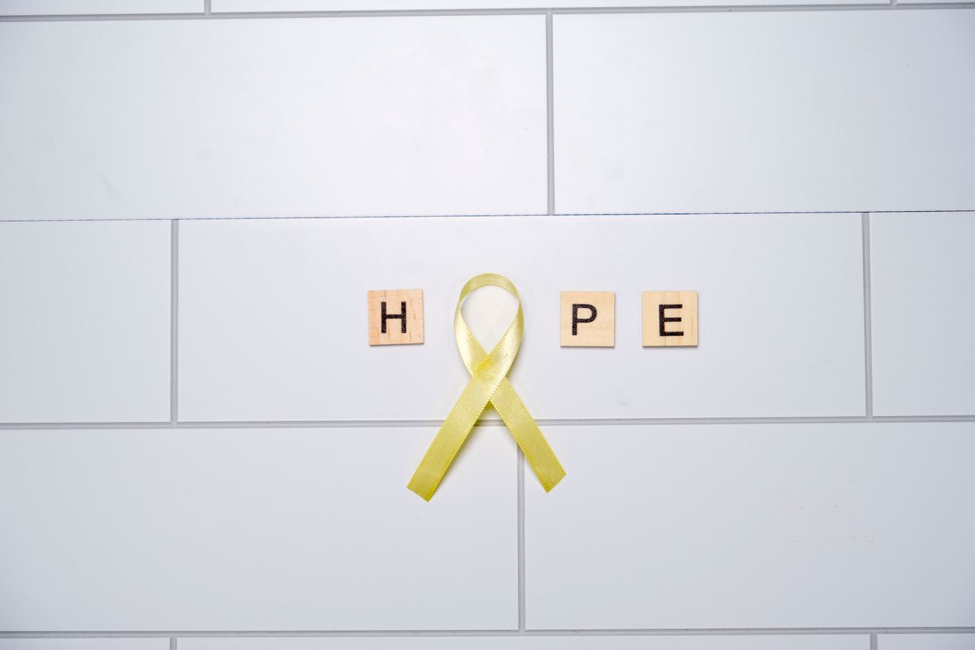 Yellow awareness ribbon on white tiles