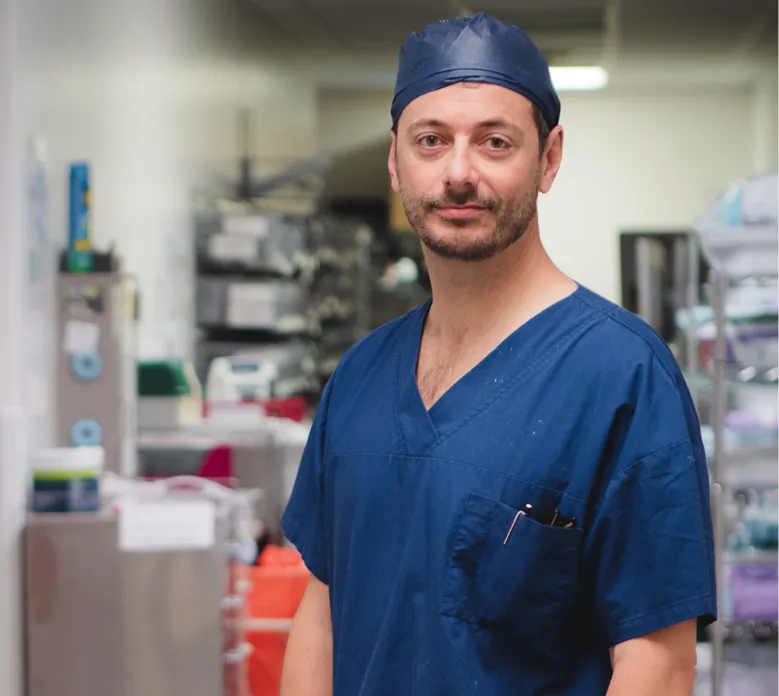 Orthopaedic surgeon wearing blue surgical scrubs and cap in hospital theatre environment