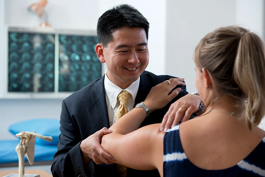 Athletic man in black compression shirt experiencing elbow pain