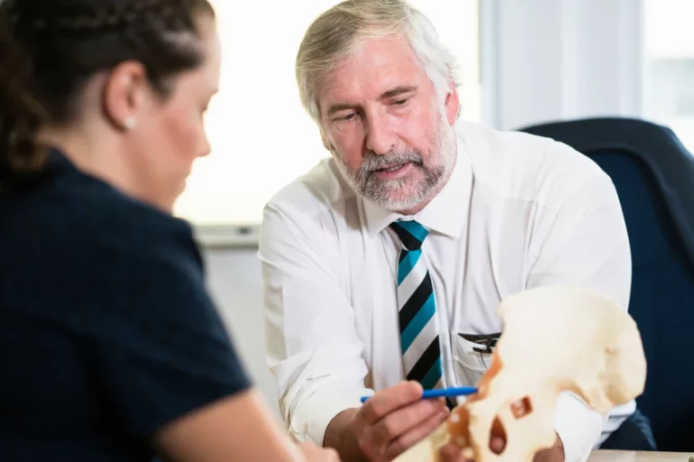 Orthopaedic specialist using model to explain hip structure to patient during medical consultation