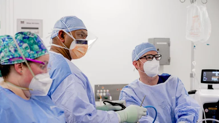 Surgical team collaborating during operation in theatre, wearing protective masks and surgical caps