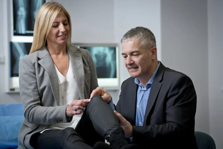 Orthopaedic surgeon examining a patient's knee during a consultation
