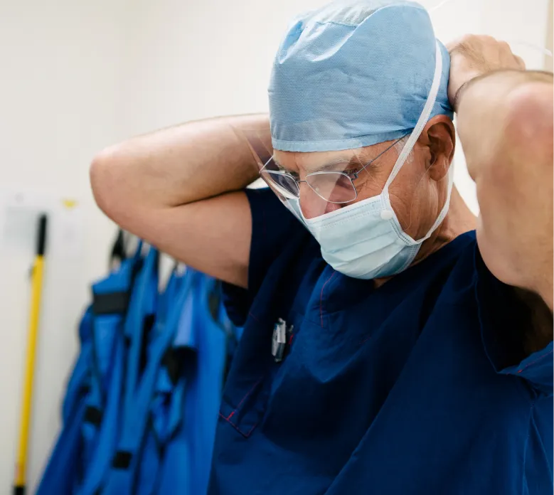 Surgeon adjusting surgical cap and mask