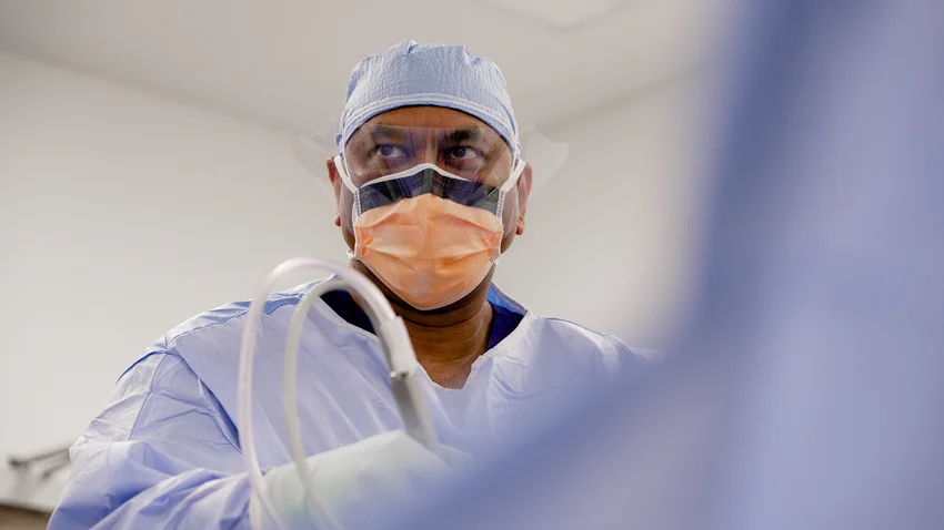 Surgical team performing operation in theatre, wearing protective masks and surgical caps