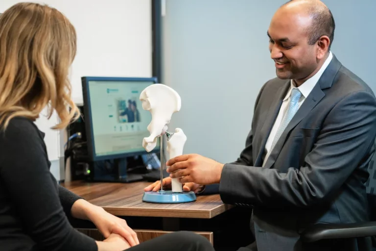 Orthopaedic specialist demonstrating hip model to patient during a consultation