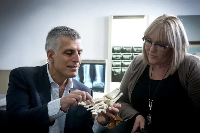 Orthopaedic surgeon demonstrating foot bone structure using anatomical model during patient consultation