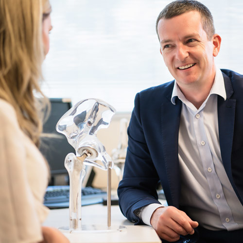 Dr Anthony Samson interacting with patient with a hip model on the desk